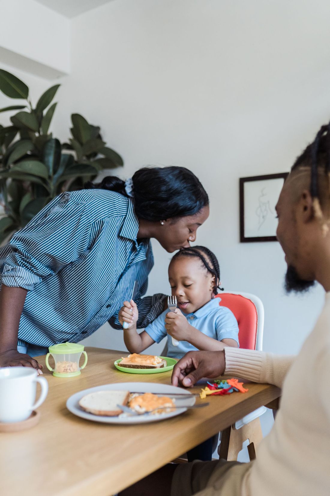 A mother kissing her daughter’s head at the breakfast table