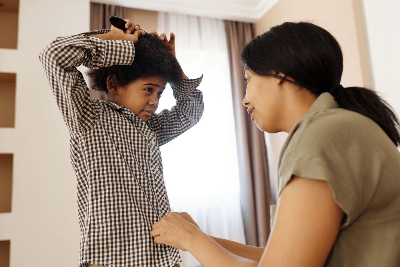 A mother helping her son put on his shirt