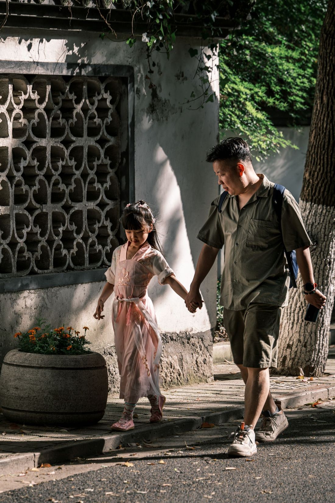 A father and daughter walking hand in hand along a street