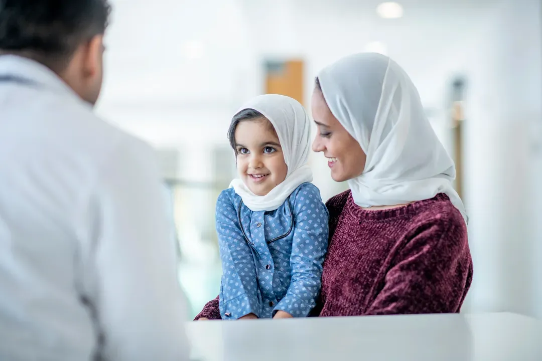 A mother and her daughter sitting together, talking with a doctor